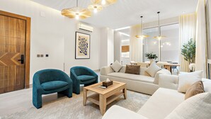 A modern living room with a sofa, two armchairs, a coffee table, and a wooden door. - Silkhaus Majidia 120 (Riyadh)