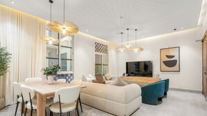 A modern living room with a sofa, dining table, chairs, and a TV. - Silkhaus Majidia 120 (Riyadh)