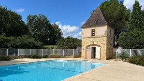 A swimming pool adjacent to a stone building with a small door and a sign above it. - Holiday Home in Perigord Noir Near Dordogne (Carsac-Aillac)