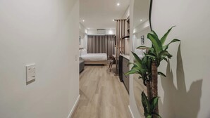 Une chambre d’hôtel moderne, équipée d’un lit, d’une table de chevet et d’un grand miroir.