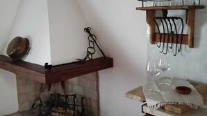 Una cocina rústica con chimenea de piedra, vigas de madera y un colgador para utensilios.