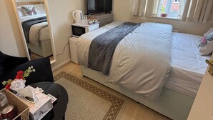 A bedroom with a bed, a TV, a desk, and a window. - Deluxe Double Room in Birmingham (West Midlands)