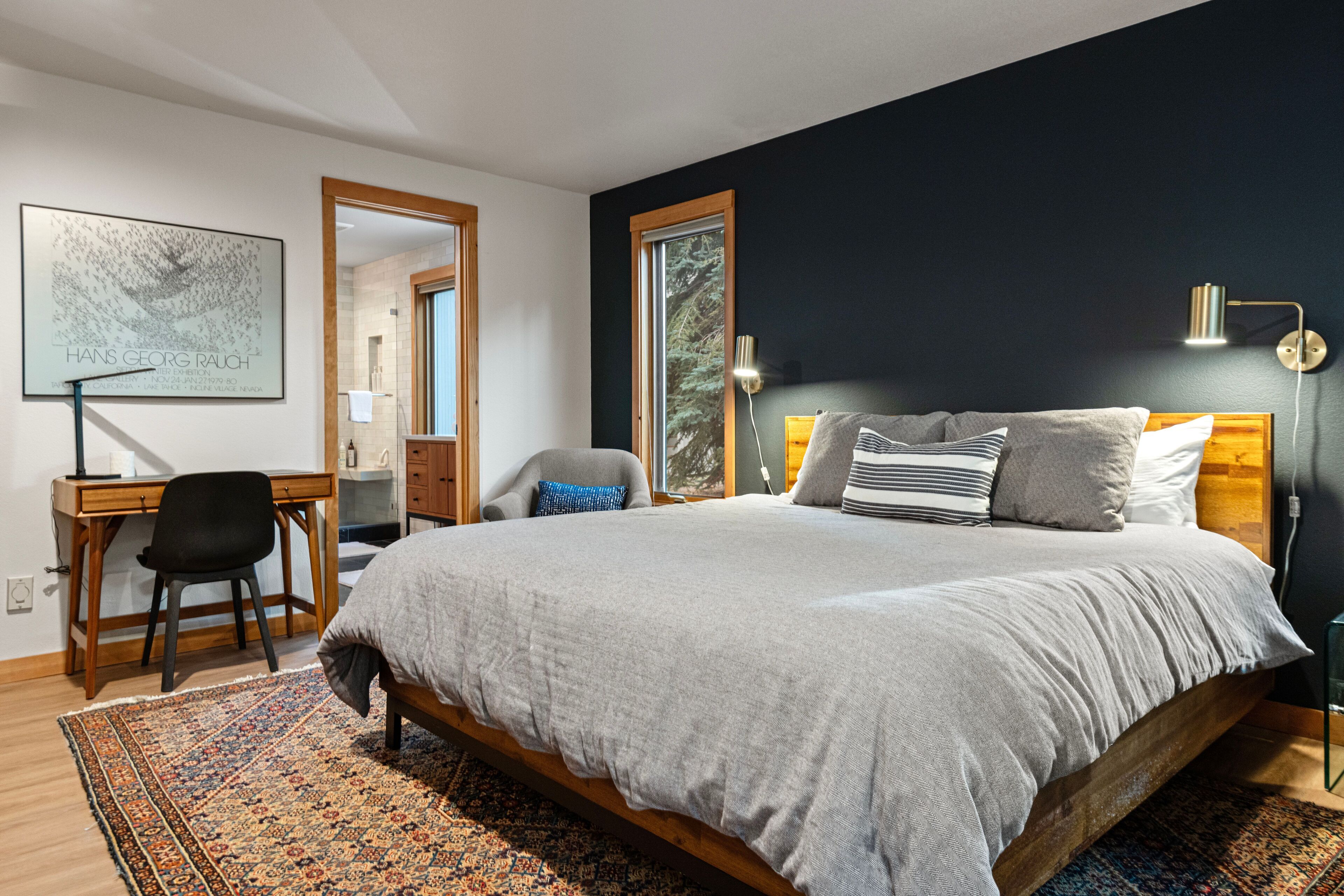 A modern bedroom with a large bed, a desk, and a chair.
