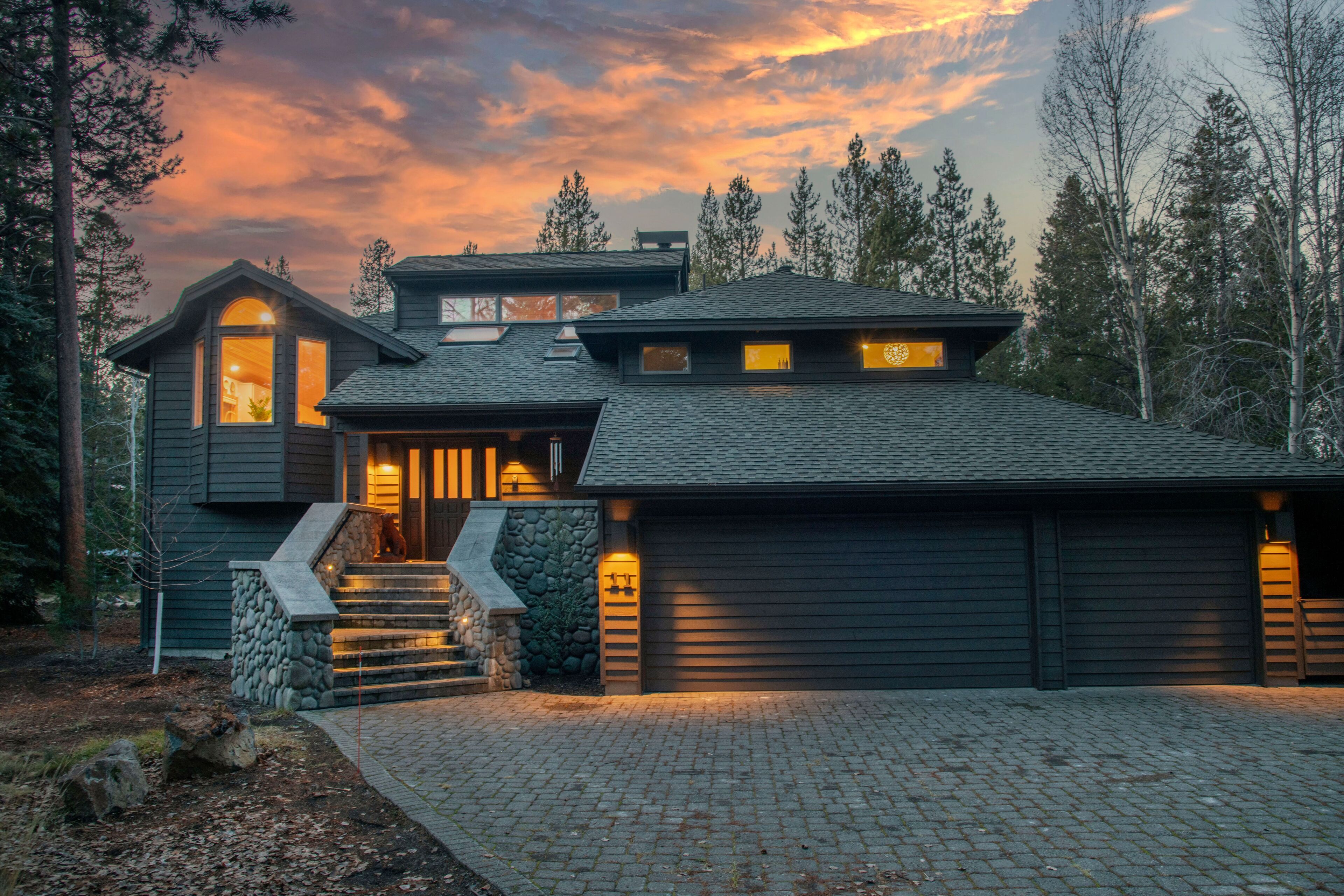 A modern two-story house with a stone staircase, a garage, and a driveway.
