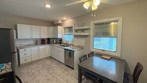 A kitchen with white cabinets, a granite countertop, a dining table with chairs, and a ceiling fan. - Charming 3-bedroom house with AC and WiFi in Appleton (Appleton)