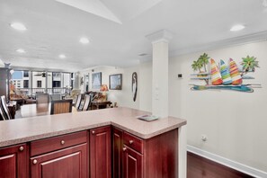 A spacious kitchen with a large island, a dining area with a view, and a wall mural of sailboats.