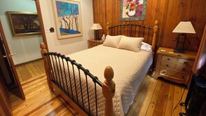 Une chambre à coucher avec un cadre de lit en bois, une couvre-lit matelassée, deux tables de chevet avec des lampes et un plancher en bois.