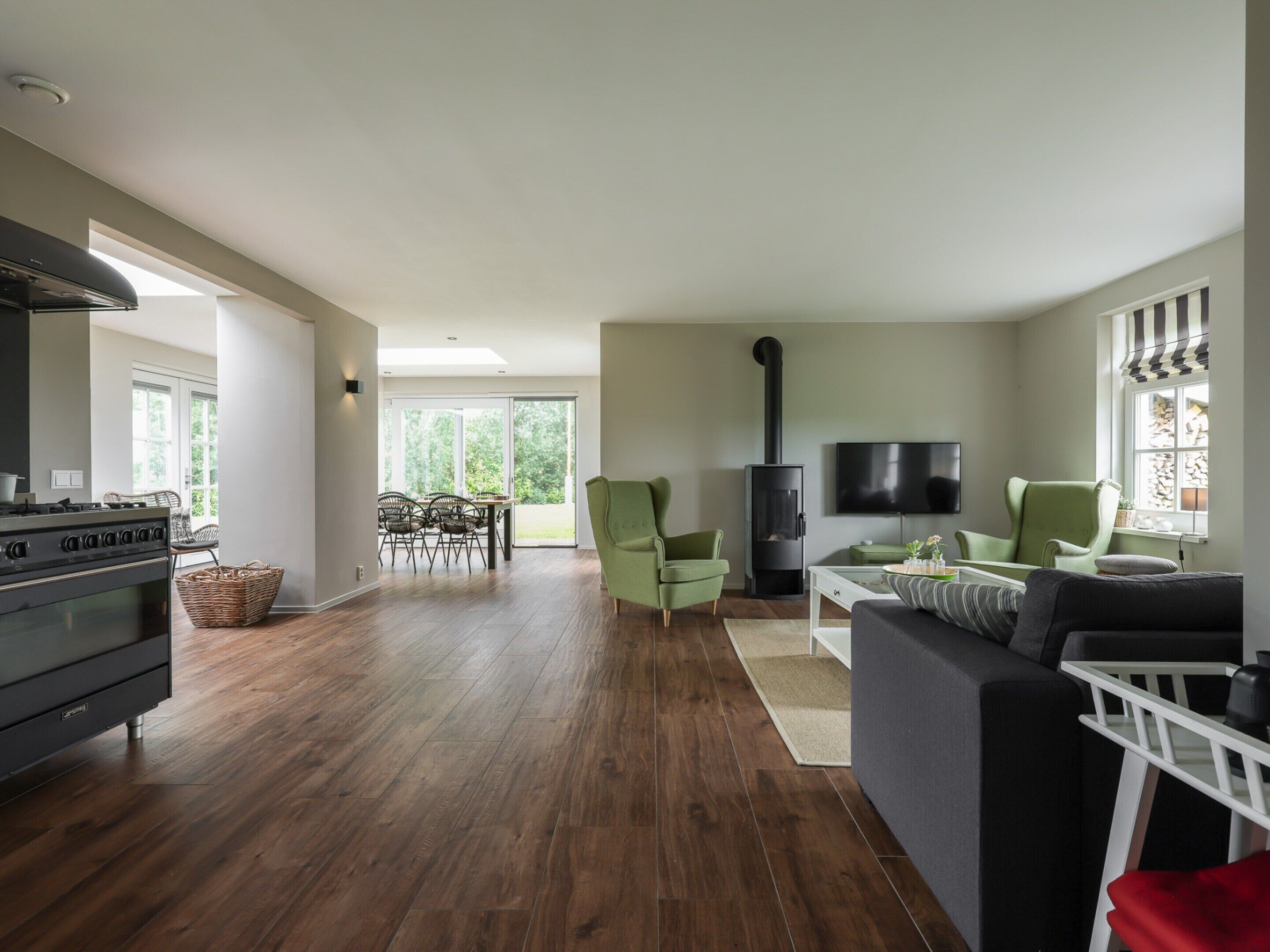 A spacious living room with a fireplace, a dining area with chairs, and a kitchen with a stove.