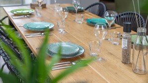 A dining table set with plates, glasses, and cutlery, with chairs around it. - Holiday Home in Zeeland With Private Pool (Wissenkerke)