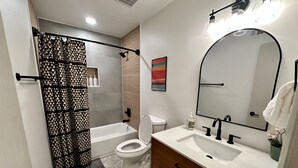 Un baño moderno con bañera, inodoro y tocador con espejo.