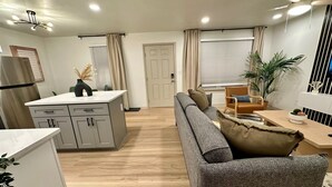 Una cocina moderna con una isla central, un sofá gris y una mesa de comedor de madera.