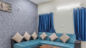Una sala de estar con un sofá modular, una mesa de centro de madera y cortinas azules.