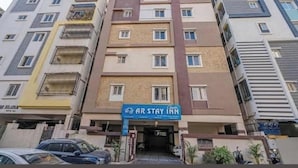 Un hotel de varios pisos con entrada central, balcones en cada planta y un cartel que dice 'AR STAY INN'.