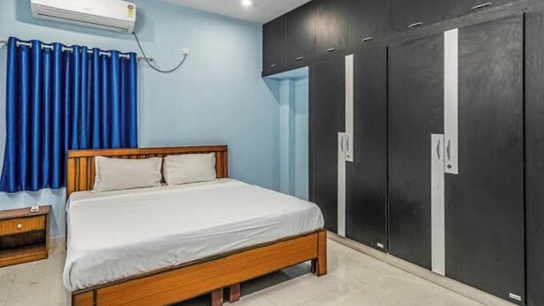 Une chambre à coucher comprenant un lit, une armoire, une table de chevet et un appareil de climatisation.