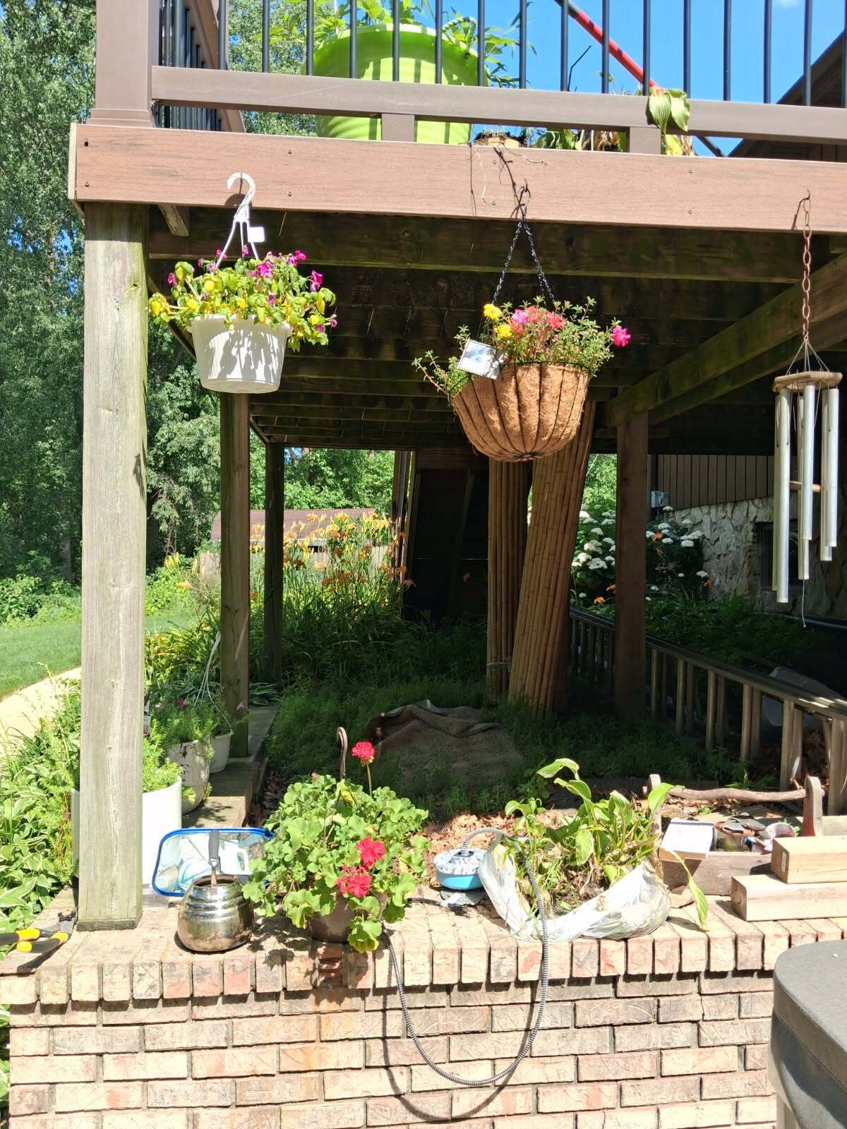 A wooden pergola with hanging planters and a brick wall.
