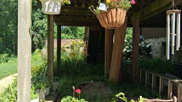 A wooden pergola with hanging planters and a brick wall.