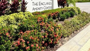 Señal para el centro de servicios The Enclaves, con un jardín ajardinado al frente.