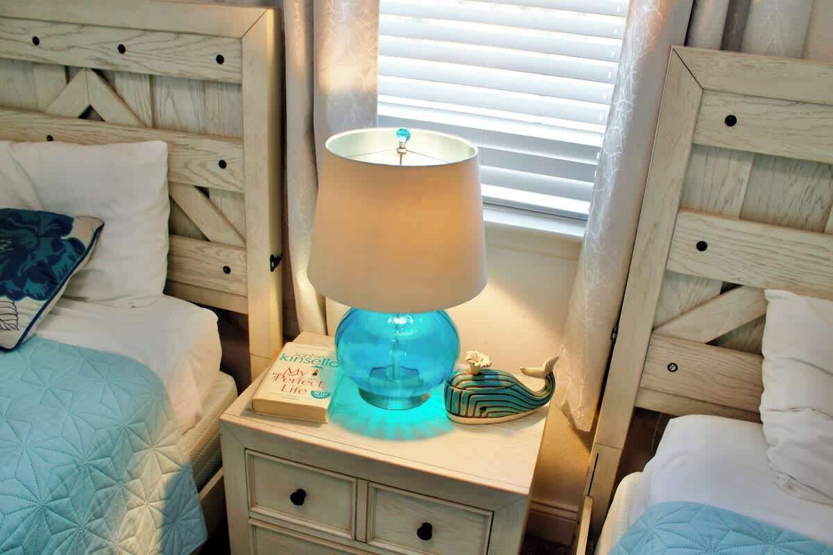 Une chambre avec deux lits, une table de chevet avec une lampe, un livre et un objet décoratif.