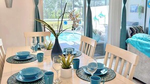 Un comedor con una mesa dispuesta para cuatro personas, con vajilla azul y una lámpara moderna.