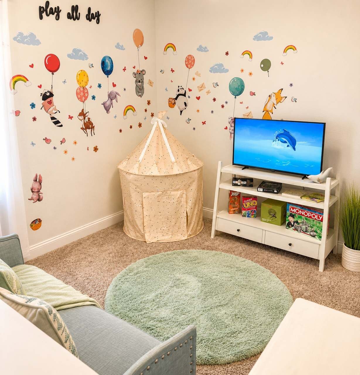 Une salle de jeux pour enfants avec une télévision, une bibliothèque et une tente de jeu.