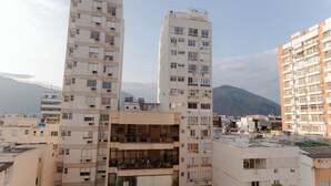 Un edificio residencial de varios pisos con balcones, ventanas amplias y montañas al fondo.