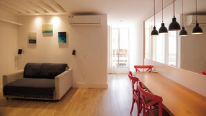 Una habitación moderna con sofá, una mesa de comedor con sillas y obras de arte en las paredes.