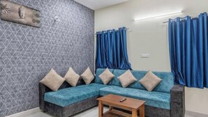 A living room with a sectional sofa, a wooden coffee table, and blue curtains. - Chic 2-bedroom apartment with AC, WiFi in fabulous Hyderabad (Hyderabad)