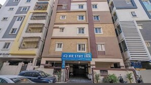 A multi-story hotel with a central entrance, balconies on each floor, and a sign for 'AR STAY INN'. - Chic 2-bedroom apartment with AC, WiFi in fabulous Hyderabad (Hyderabad)