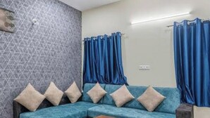 Una sala de estar con un sofá modular, una mesa de centro de madera y cortinas azules.