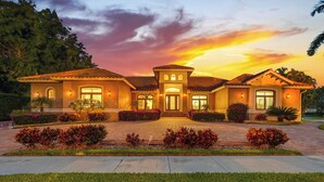 A Mediterranean-style house with a tiled roof, a central entrance, and a well-maintained garden with shrubs and a lawn.