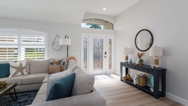 A modern living room with a sofa, a console table with lamps, and a decorative mirror.