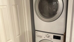 Une machine à laver et un sèche-linge superposés, installés dans un couloir.
