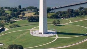 Une grande structure en forme d’obélisque, de couleur blanche, est entourée d’un parc circulaire agrémenté de sentiers.