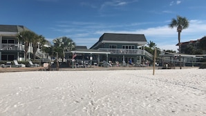 A beachfront property with a covered patio area, palm trees, and a building with a balcony.