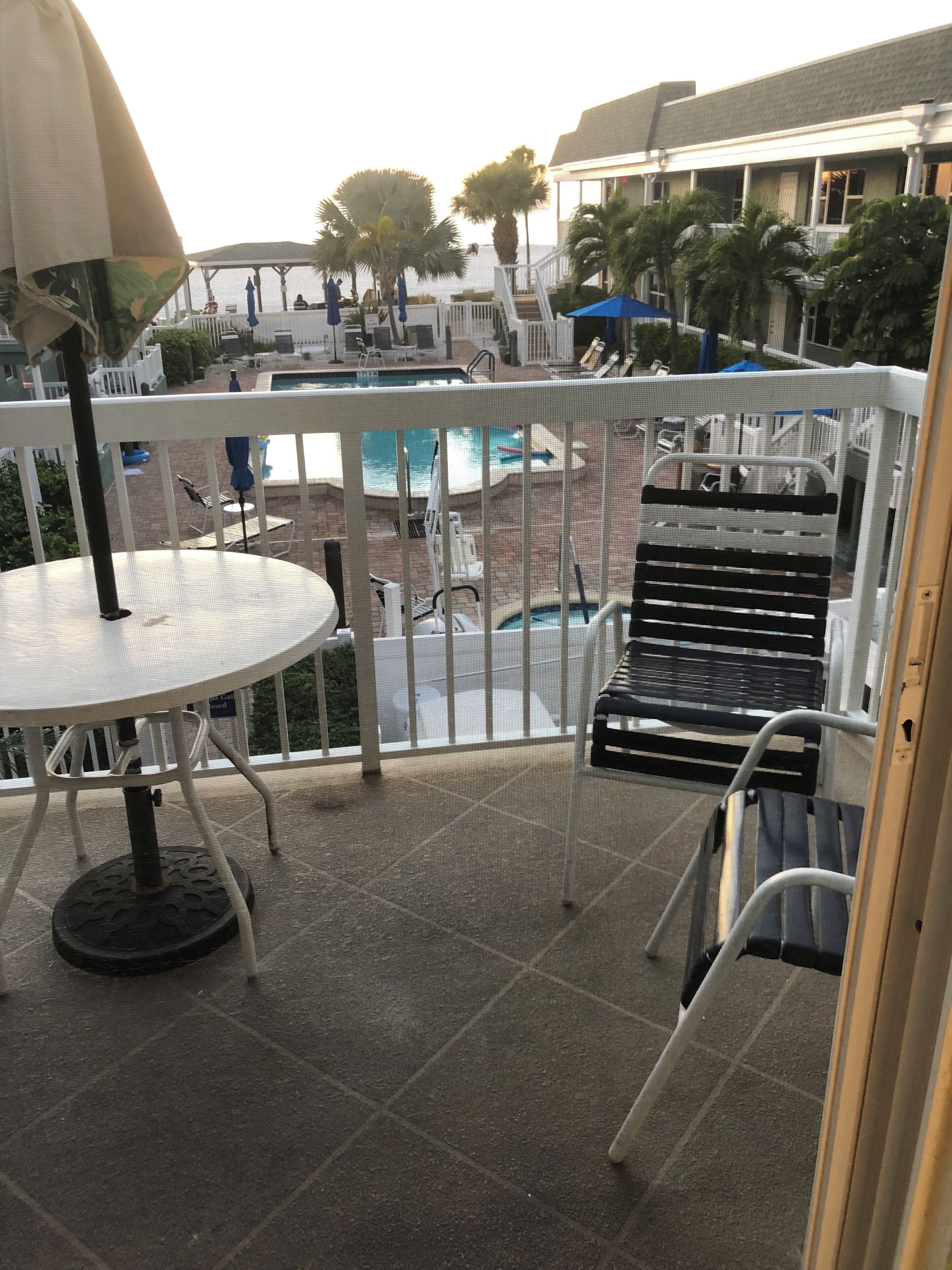 A pool area with a covered seating area, a pool, and a view of the surrounding buildings.