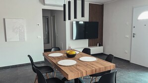 Een moderne eetruimte met een houten tafel, zwarte stoelen en een schaal met fruit.
