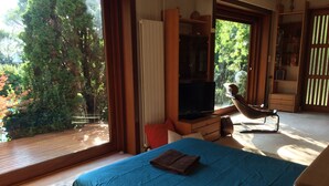 A bedroom with a bed, a TV, and a chair. - Architect-designed villa in a garden paradise with 13x6 pool and tennis court (saint-jean)
