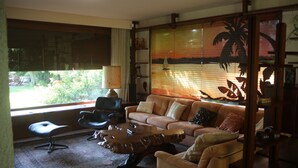 A living room with a sofa, armchairs, a coffee table, and a large window with a view of greenery. - Architect-designed villa in a garden paradise with 13x6 pool and tennis court (saint-jean)