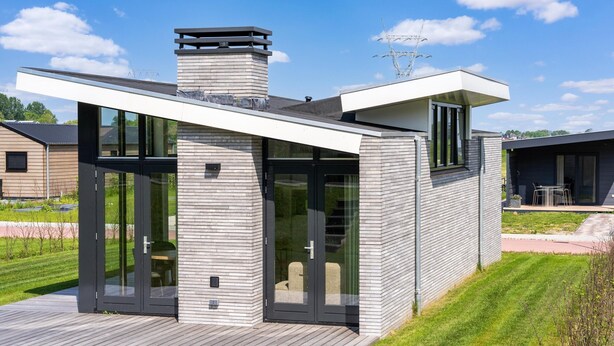 Une maison moderne avec un toit plat, de grandes fenêtres et une terrasse.