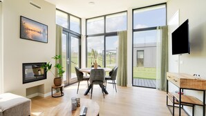 Un salon spacieux doté d’une grande fenêtre, d’un coin repas, d’un téléviseur et d’un espace salon confortable.