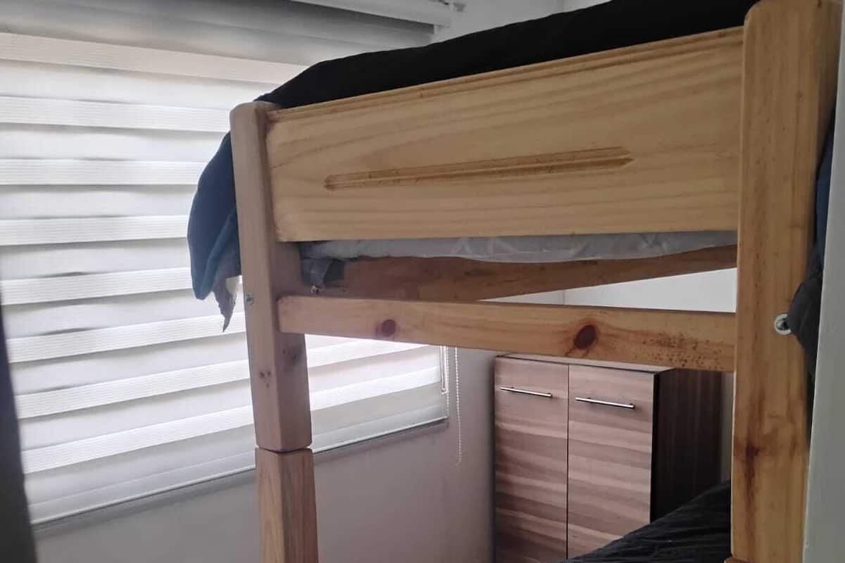 Un llit amb lliteres de fusta, un matalàs negre i un calaix petit.