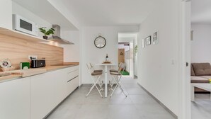 Eine moderne Küche mit weißen Schränken, einer Holz Arbeitsplatte und einer eingebauten Mikrowelle.