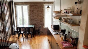 A kitchen with a wooden table and chairs, a brick wall, and a window.