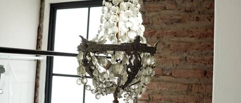 A chandelier in a room with exposed brick walls and a window.