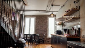 A kitchen with a brick wall, wooden floor, and a dining area with chairs.