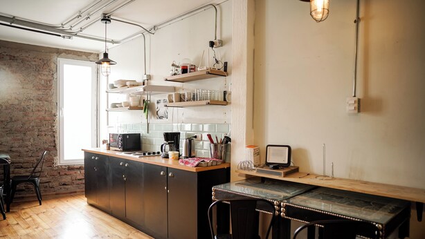 A kitchen with wooden cabinets, a dining table, and a brick wall.