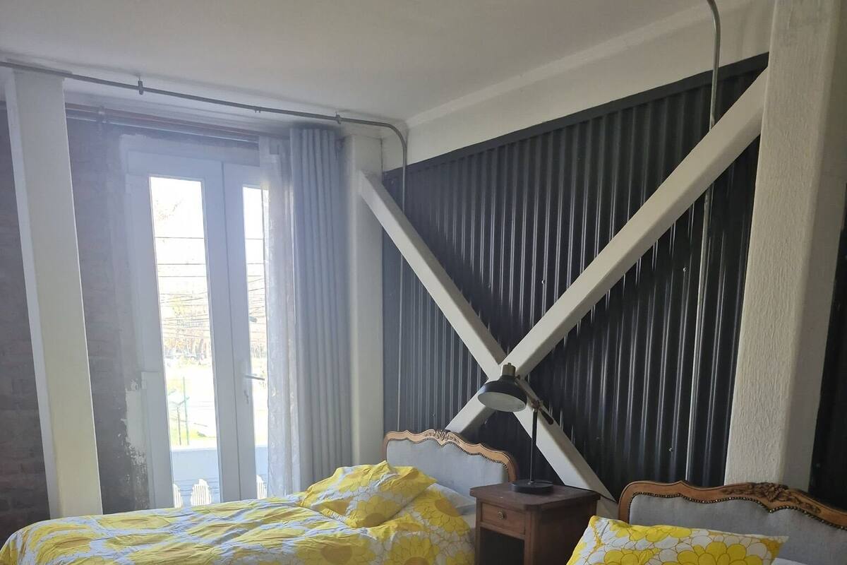 Camera d'albergo con due letti, ognuno con copriletto floreale, pavimento in legno e finestra con tende.