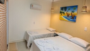 Camera d'albergo con due letti, un quadro raffigurante una spiaggia, una lampada a soffitto e un condizionatore d'aria.