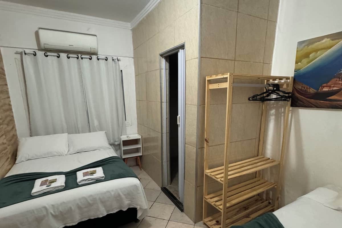 Ein Hotelzimmer mit zwei Betten, einer Holzregaleinrichtung, einem Gemälde an der Wand und einer Tür zum Badezimmer.