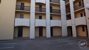 Un immeuble à plusieurs étages, doté de balcons et d’un parking situé à l’avant.